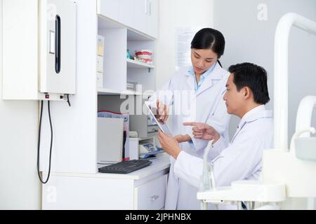 Dentiste et son assistant discutant des informations sur une tablette Banque D'Images