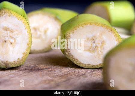 banane verte non mûre coupée en morceaux, banane avec zeste vert sur la table pendant la cuisson Banque D'Images