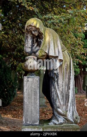 Statue d'une femme en deuil sur un fond d'arbres dans le cimetière Dean, Édimbourg, Écosse, Royaume-Uni. Banque D'Images
