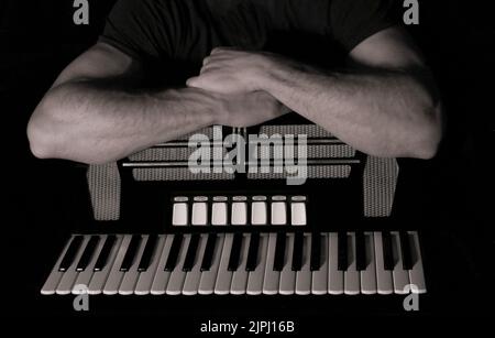 Image en noir et blanc d'un accordéoniste et de ses bras musculaires reposant sur son accordéon bien-aimé Banque D'Images