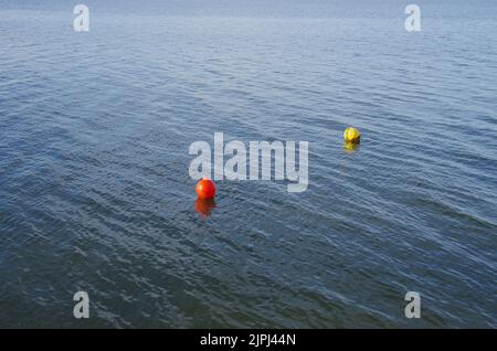 Une bouée rouge et une bouée jaune flottent sur l'eau. Banque D'Images