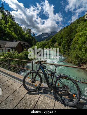 Un plan vertical d'une rivière qui coule d'un pont avec un vélo et des collines boisées des deux côtés Banque D'Images