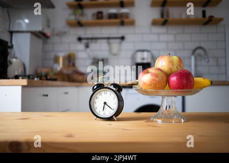 réveil vintage et fruits frais sur la table de cuisine à jeun par intermittence Banque D'Images