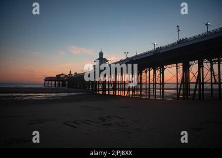 Blackpool - North Pier au coucher du soleil et le mot « MUM » écrit dans le sable sur la plage - UK Summer Holiday destinations, 2022 Banque D'Images