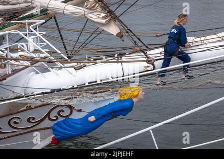 Sunderland, Royaume-Uni - 13 juillet 2018: Un membre de l'équipage travaille le bowscrit sous le regard de la figure de proue du navire norvégien à grande hauteur, Christian Radich. Banque D'Images