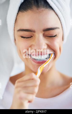Vous les verrez étinceler quand je suis terminé. Une belle jeune femme se brossant les dents dans la salle de bains à la maison. Banque D'Images