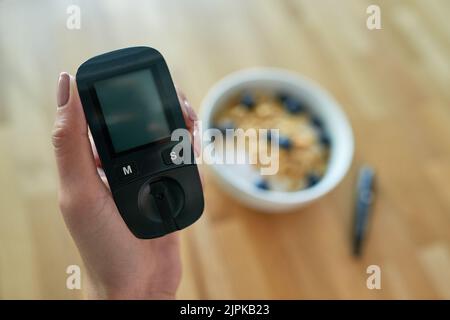 Mesurer son taux de sucre dans le sang. Gros plan d'une femme méconnaissable qui teste son taux de sucre dans le sang avec un glucomètre. Banque D'Images