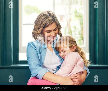 Prendre une petite sieste dans les bras de mummys. Une petite fille fatiguée se reposant avec ses yeux fermés dans les bras de ses mères. Banque D'Images