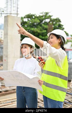 Une jeune femme asiatique professionnelle inspecteur de construction expliquant le plan de construction à une femme architecte. Banque D'Images