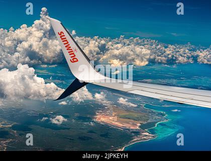 Retour de vacances à Holguin Cuba. Un avion Sunwing survole la côte de Cuba sur fond de nuages lourds au-dessus de l'océan Atlantique. Banque D'Images