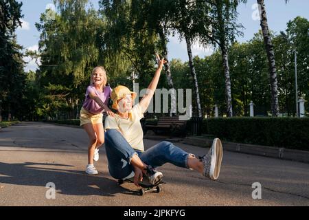 Fille et mère gaies jouant avec le skateboard dans le parc. Banque D'Images