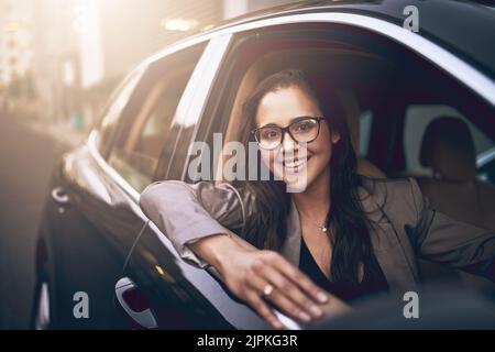 Éteint pour démarrer une journée réussie. Portrait d'une jeune femme d'affaires conduisant une voiture. Banque D'Images