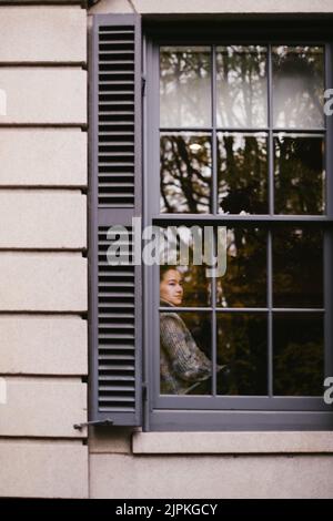 La jeune femme asiatique regarde la fenêtre de la maison en automne Banque D'Images