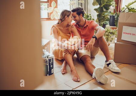 Romance, amusement et un moment intime entre un couple se déplaçant dans une nouvelle maison. Les jeunes amoureux sont affectueux, flirtant et appréciant une conversation Banque D'Images