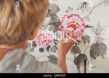 Femme âgée peignant des fleurs dans un studio d'art Banque D'Images