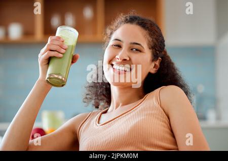 Smoothie vert, boisson et jus sain pour la perte de poids, le détox ou le régime de petit-déjeuner dans la salle de séjour à la maison. Portrait d'une femme souriante et heureuse qui boit des fruits Banque D'Images