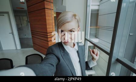 POV de la jeune femme d'affaires en costume prendre un selfie photo tenant un smartphone et s'amuser dans le bureau moderne à l'intérieur Banque D'Images