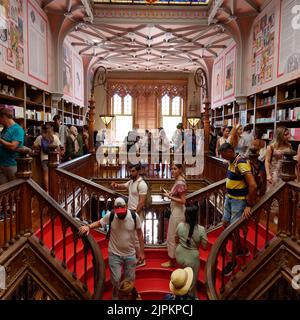 Intérieur de la belle Livraria Lello aka Lello Bookstore à Porto, Portugal. Le magasin est bondé et les gens descendent le célèbre escalier rouge. Banque D'Images