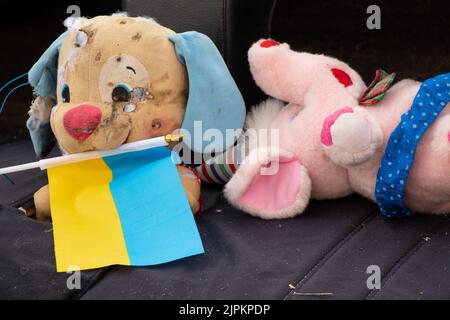 Un jouet sale cassé pour enfants et le drapeau de l'Ukraine se trouvent dans la cour pendant la guerre en Ukraine, la mort d'enfants aux mains du soldie russe Banque D'Images