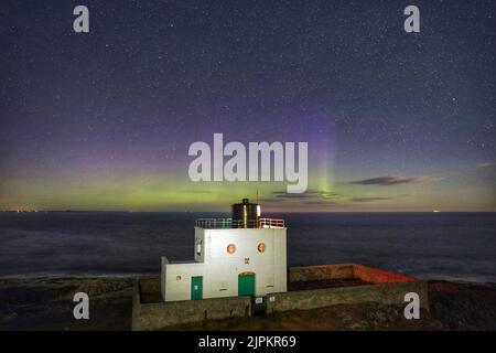 Les aurores boréales, mieux connues sous le nom de lumières nordiques, apparaissent tôt le matin au-dessus du phare de Bamburgh, dans le Northumberland. Au Royaume-Uni, le soleil et les averses seront visibles après un mélange de chaleur intense et de pluie torrentielle au cours des dernières semaines. Date de la photo: Vendredi 19 août 2022. Banque D'Images