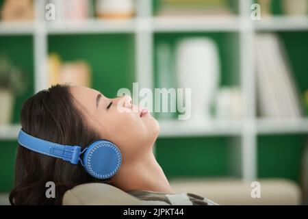 Femme dans un casque se détendant et écoutant de la musique Banque D'Images