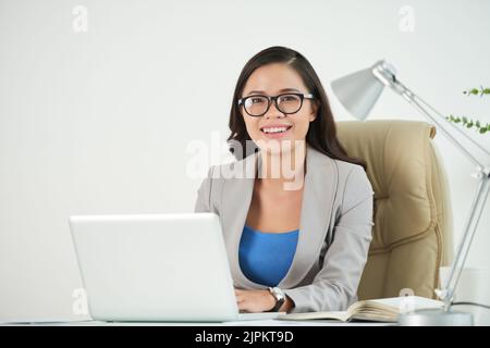 Femme entrepreneure souriante et attirante travaillant sur un ordinateur portable Banque D'Images