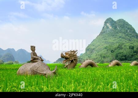 Sculptures en paille d'un dragon chinois et d'un fermier à cheval sur un Buffalo d'eau dans un champ de riz, dans le fond des montagnes Karst. Yangshuo, Chine. Banque D'Images
