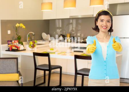 Bonne femme vietnamienne dans des gants en caoutchouc montrant le pouce vers le haut Banque D'Images