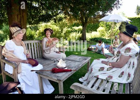 Femmes vêtues de costumes de l'époque Regency (1811-20), assises dans le jardin de la Maison Jane Austen, à Chawton, près d'Alton, Hampshire, Royaume-Uni. Banque D'Images