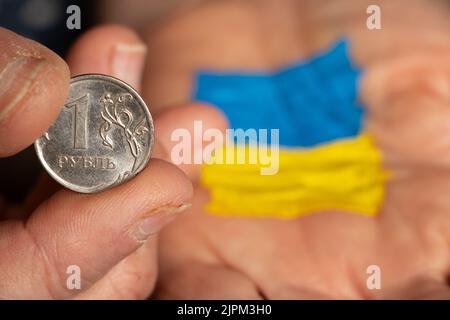 Rouble russe dans la main d'une femme et le drapeau de l'Ukraine jaune-bleu sur la seconde main d'une femme, l'effondrement du rouble, défaut en Russie Banque D'Images