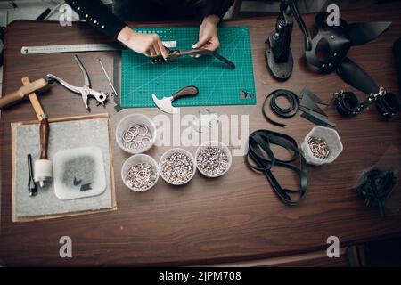 Tanner femme faisant des marchandises de ceinture de harnais en cuir sur l'atelier.Processus de travail de l'artisan du cuir. Banque D'Images