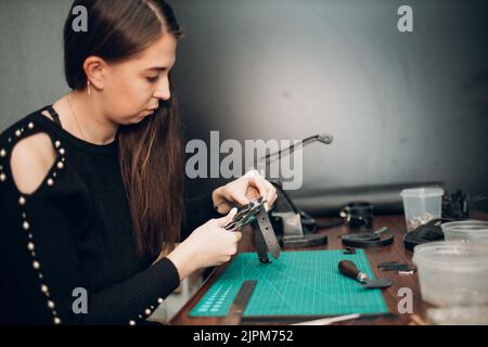 Tanner femme faisant des marchandises de ceinture de harnais en cuir sur l'atelier.Processus de travail de l'artisan du cuir. Banque D'Images