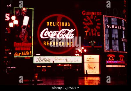 Enseignes publicitaires Neon à Night Piccadilly Circus, Londres, Angleterre, Royaume-Uni 1957 - panneau Coca Cola au-dessus du restaurant Fortes, horloge Guinness, batteries toujours prêtes, Schweppes, campagne de promotion de la sécurité routière Zebra Crossing Banque D'Images