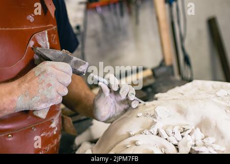 Le sculpteur d'homme crée le buste sculptant gypse homme femme sculpture avec marteau.Atelier de création d'artisanat de statue. Banque D'Images