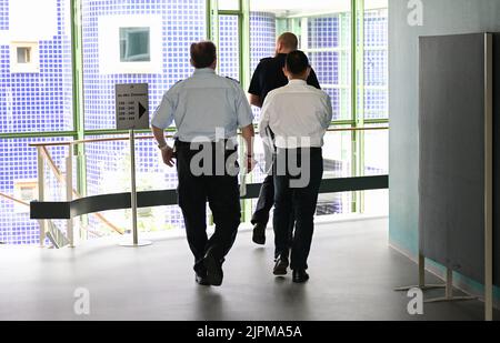 Pforzheim, Allemagne. 19th août 2022. Le défendeur r) dans un procès pour le vol d'environ 38 kilogrammes de copeaux d'or est conduit dans une salle d'audience par le personnel du tribunal. L'homme aurait pillé les copeaux d'or d'une entreprise de bijoux de Pforzheim pendant une longue période. Le procès a lieu au bureau de la Cour régionale de Karlsruhe à Pforzheim. Credit: Bernd Weißbrod/dpa/Alay Live News Banque D'Images