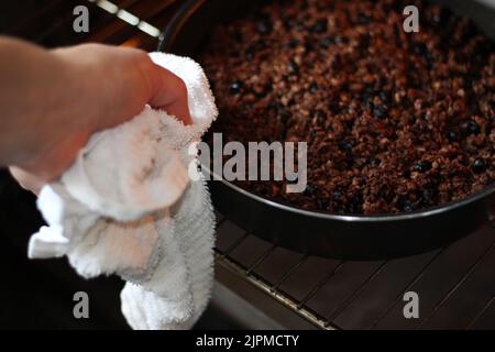 Femme qui sort du four du granola fraîchement cuit. Petit déjeuner maison dessert. Banque D'Images