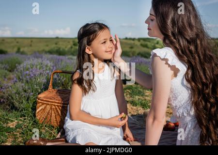 bonne femme touchant le visage de la fille tout en ayant pique-nique dans la prairie Banque D'Images