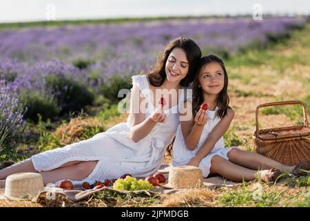 bonne mère et fille tenant des fraises pendant le pique-nique sur le terrain Banque D'Images