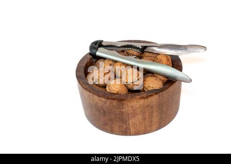 Noix entières dans un bol en bois avec casse-noisette isolé sur fond blanc Banque D'Images