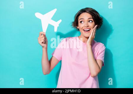 Portrait photo de jeune joli magnifique fille mignon toucher joues excités look intéressé tenir blanc avion de papier isolé sur fond de couleur cyan Banque D'Images