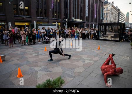 Helsinki, Finlande. 18th août 2022. Les gens regardent des spectacles pendant la nuit des arts à Mikonkatu à Helsinki, en Finlande, le 18 août 2022. La nuit des arts, aujourd'hui une tradition d'Helsinki, a été célébrée jeudi, avec diverses manifestations artistiques organisées dans différents lieux. De nombreux musées offrent une entrée gratuite et certaines galeries et musées prolongent leurs heures d'ouverture pendant l'événement. Credit: Matti Matikainen/Xinhua/Alamy Live News Banque D'Images