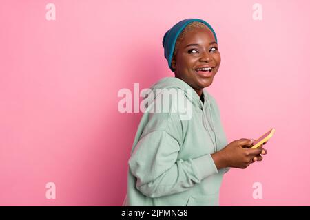 Profil photo de côté de mignonne riant surf femelle dans les médias sociaux voir dans l'espace vide nouvelle annonce de téléphone isolé sur fond rose couleur Banque D'Images