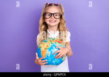 Photo de charmante petite fille queues lunettes hug globe terre école shopping habillé élégant blanc look isolé sur fond violet couleur Banque D'Images