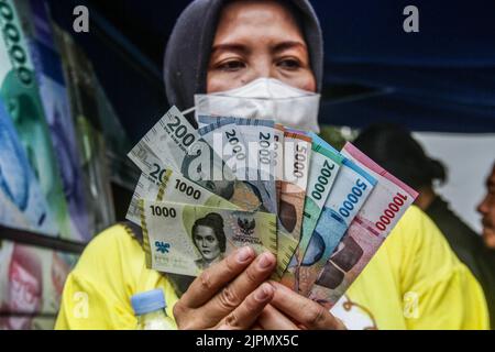 Bandung, Indonésie. 19th août 2022. Une femme affiche de nouveaux billets indonésiens à Bandung. Le gouvernement indonésien et Bank Indonesia ont lancé sept nouveaux billets pour commémorer le 77th anniversaire de l'indépendance de l'Indonésie. Crédit : SOPA Images Limited/Alamy Live News Banque D'Images