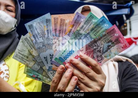 Bandung, Indonésie. 19th août 2022. Une femme affiche de nouveaux billets indonésiens à Bandung. Le gouvernement indonésien et Bank Indonesia ont lancé sept nouveaux billets pour commémorer le 77th anniversaire de l'indépendance de l'Indonésie. Crédit : SOPA Images Limited/Alamy Live News Banque D'Images