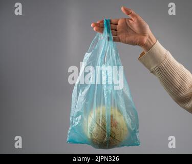 Une femme tient un globe dans un sac en plastique sur fond blanc. Banque D'Images