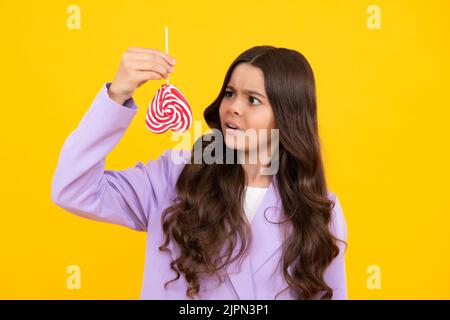 Une jeune fille tient le caramel à la lylipop sur fond jaune, boutique de bonbons. Adolescent avec suckers de bonbons. Banque D'Images