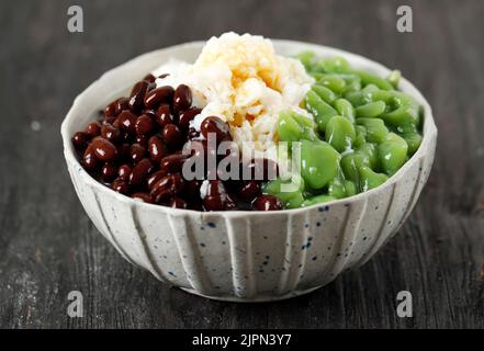 Cendol Malaysian dessert avec glace rasée et haricots rouges, sur une table en bois noir Banque D'Images