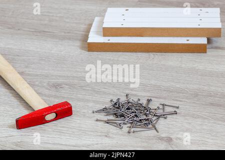 Outils de construction au sol ; marteau, clous et aggloméré. Banque D'Images