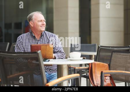 Joyeux homme mûr avec menu dans un café extérieur Banque D'Images